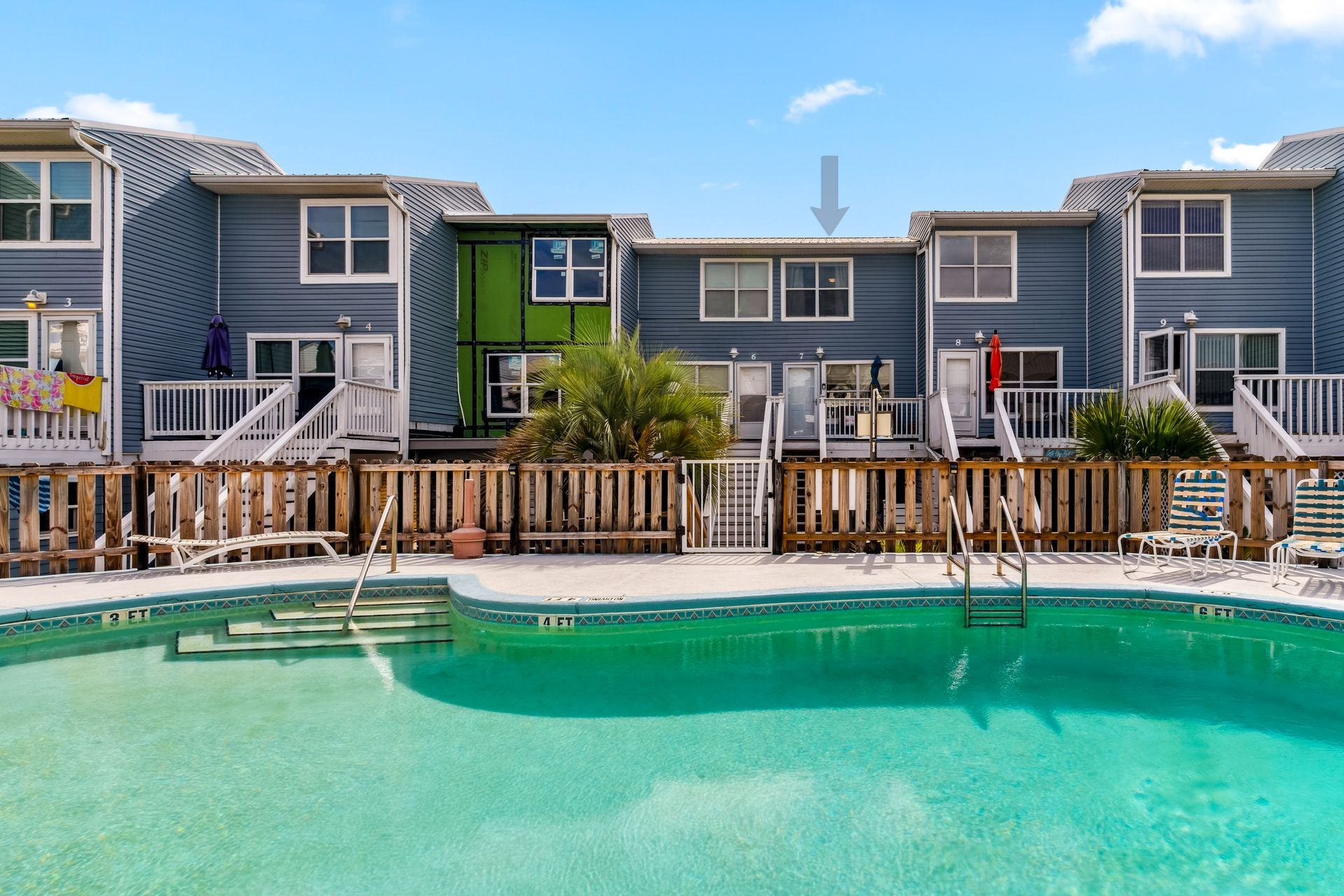 A large swimming pool is in front of a row of houses.