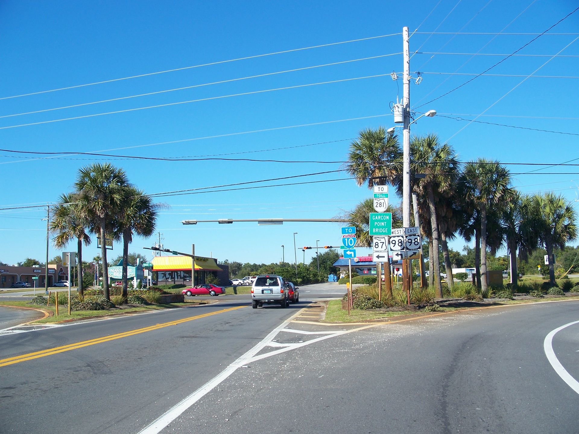 A car is driving down a street with palm trees on both sides