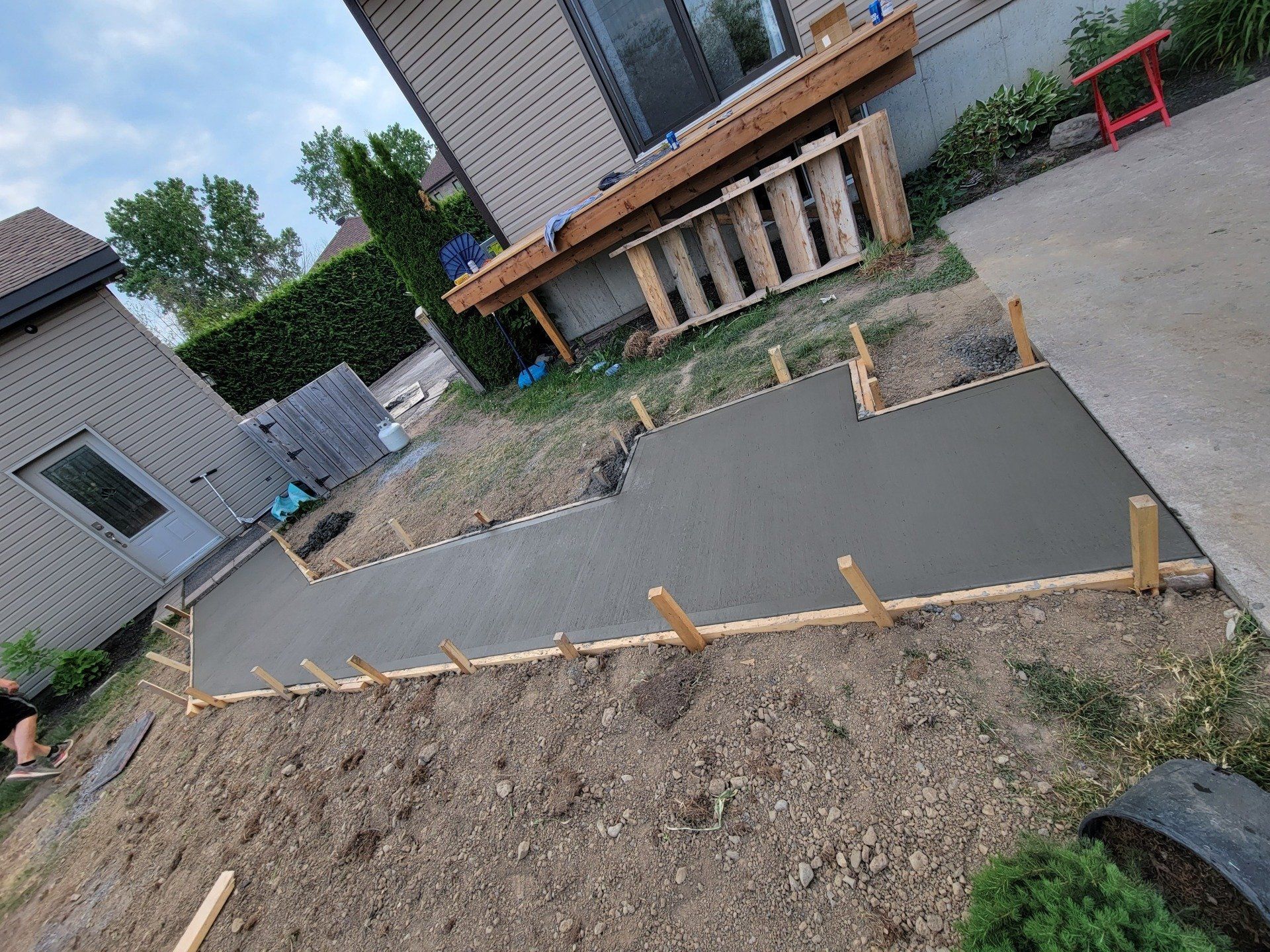 A concrete walkway is being built in the backyard of a house.