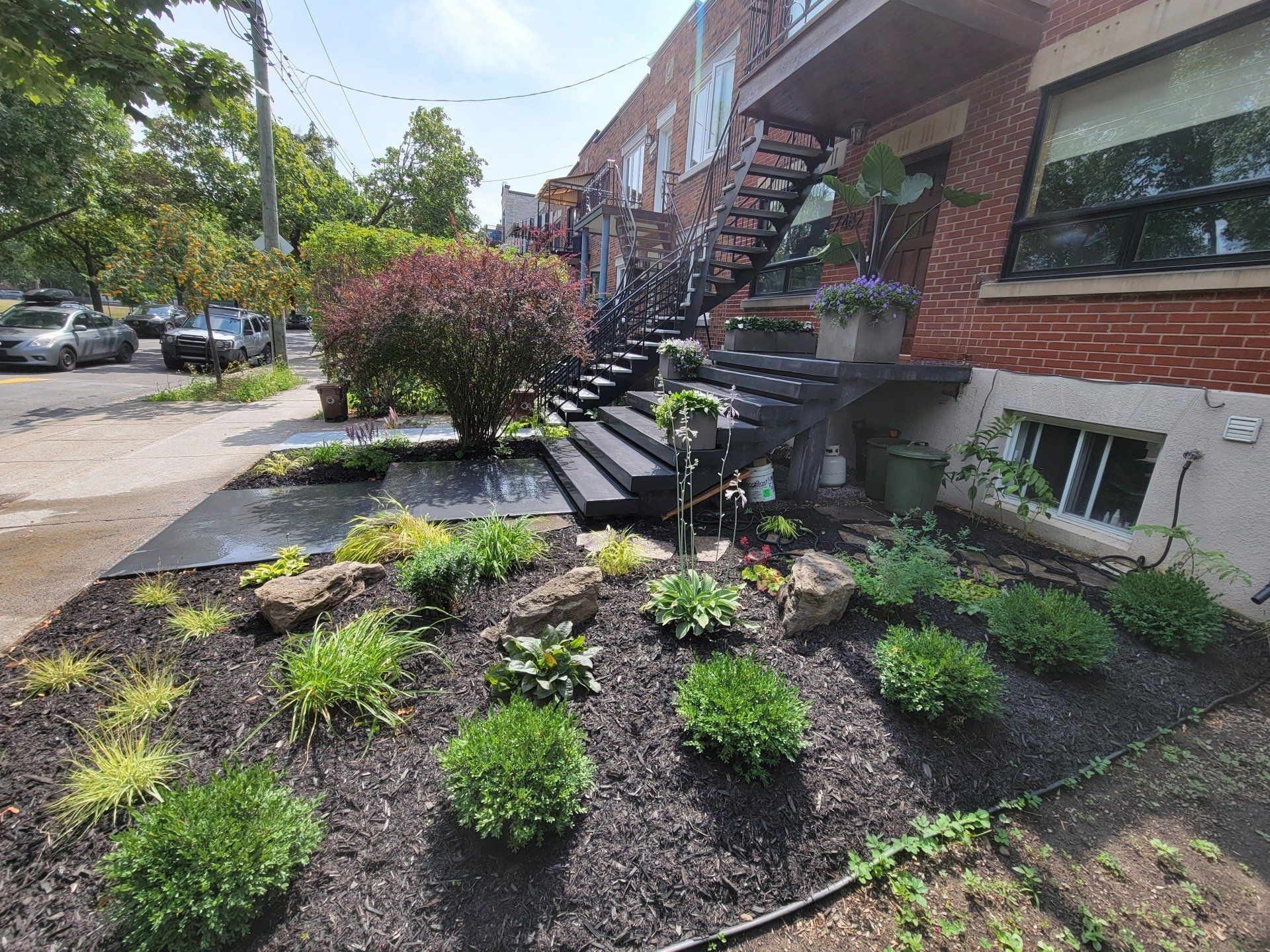A brick building with stairs and a garden in front of it.