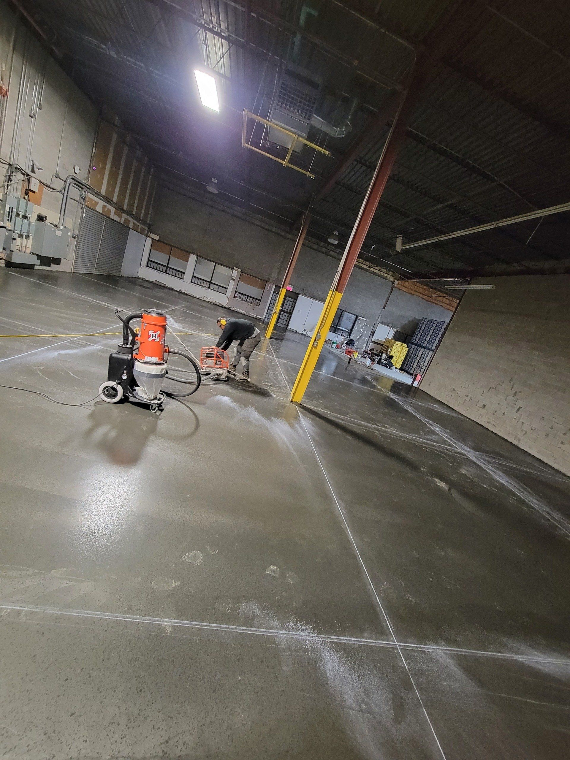 A man is working on a concrete floor in a warehouse.