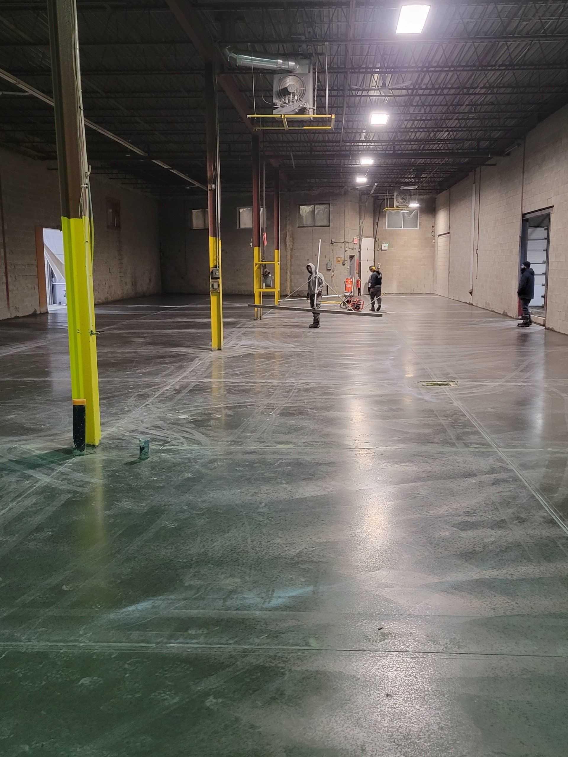 A large empty warehouse with a concrete floor and yellow poles.