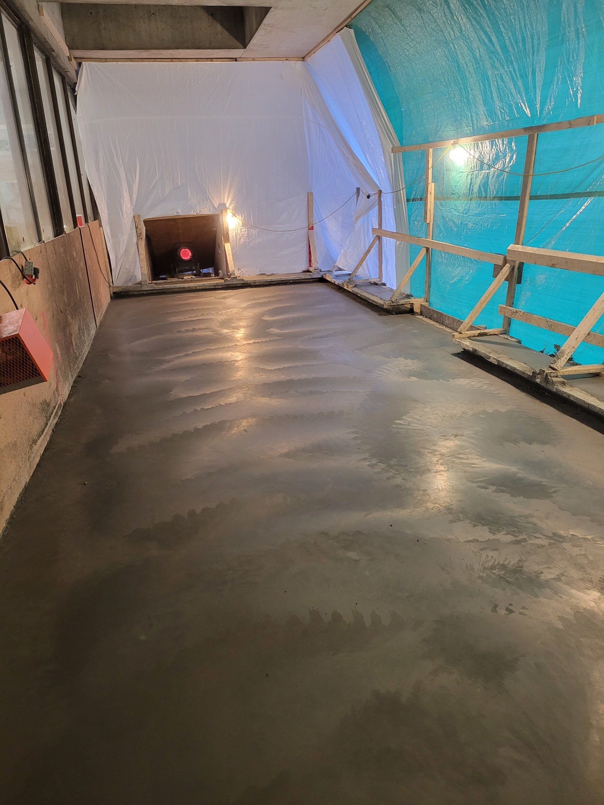 A room with a concrete floor and a blue tarp on the wall.