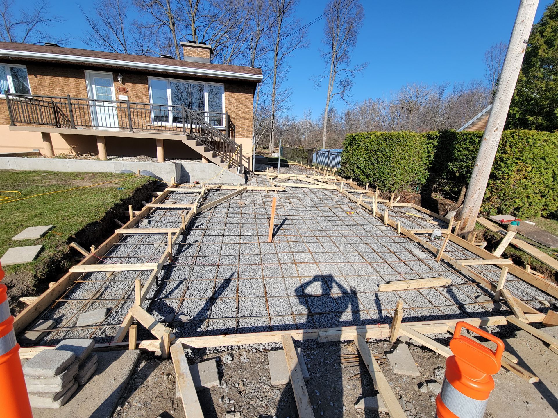 Chantier : coffrage d'allée en béton avec fer à béton, ossature bois, prêt à être coulé à proximité d'une maison.