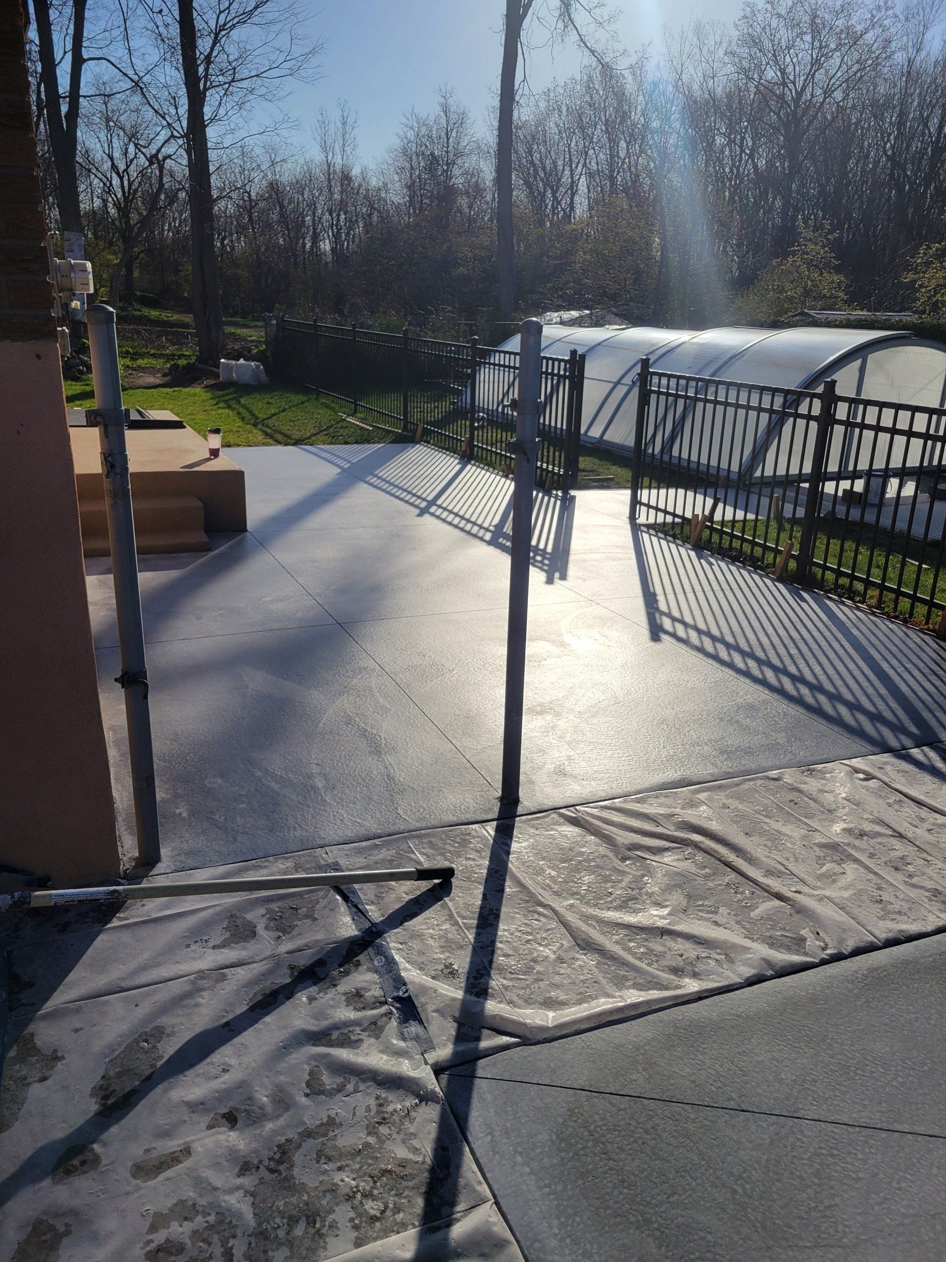 Un patio en béton avec une clôture et des arbres en arrière-plan