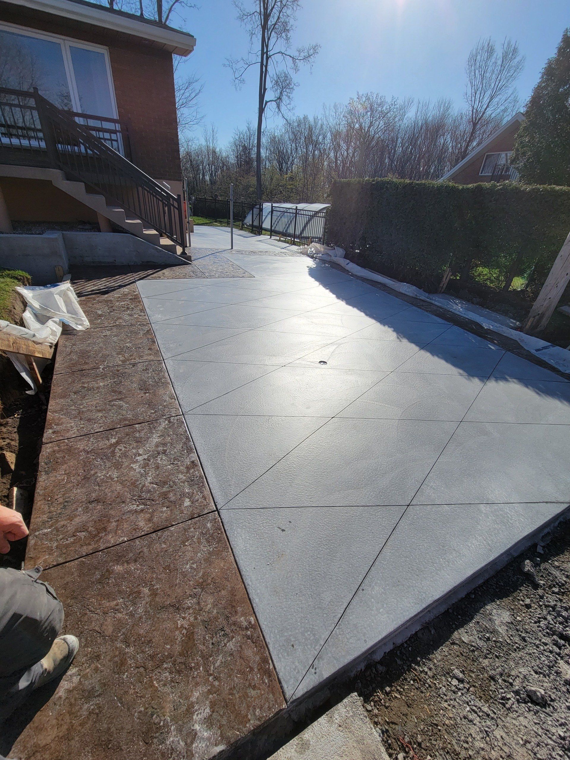 A person is working on a concrete driveway in front of a house.