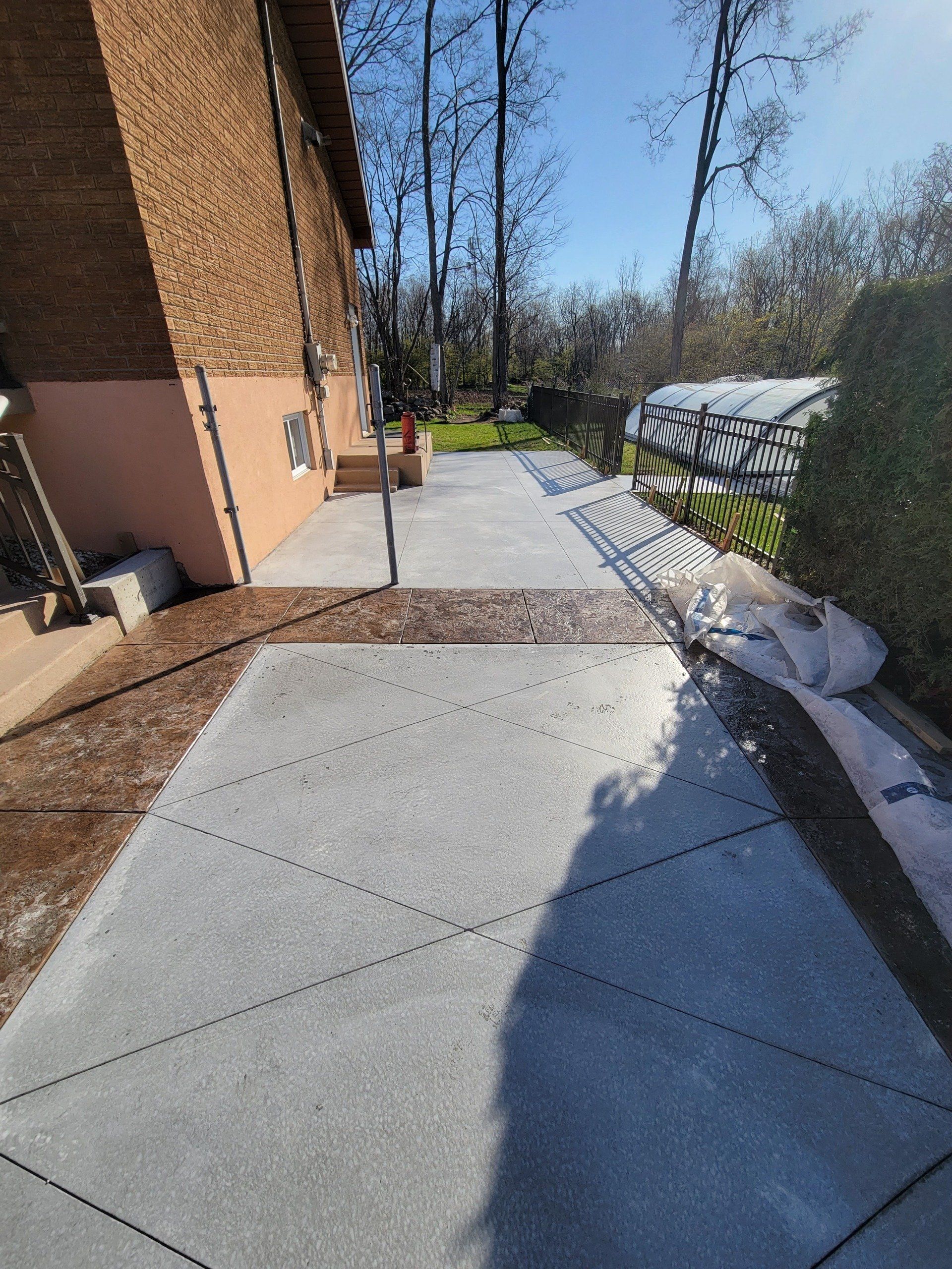 A concrete walkway leading to a house with trees in the background