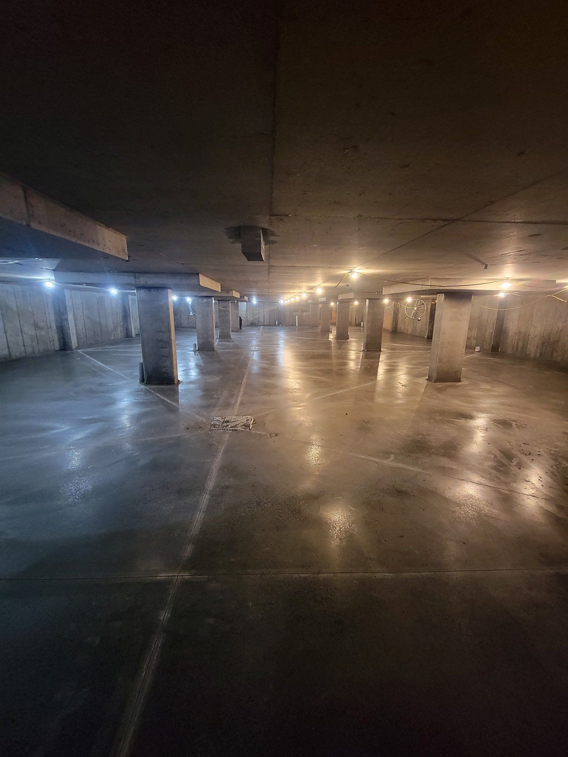 An empty parking garage with a lot of columns and lights.