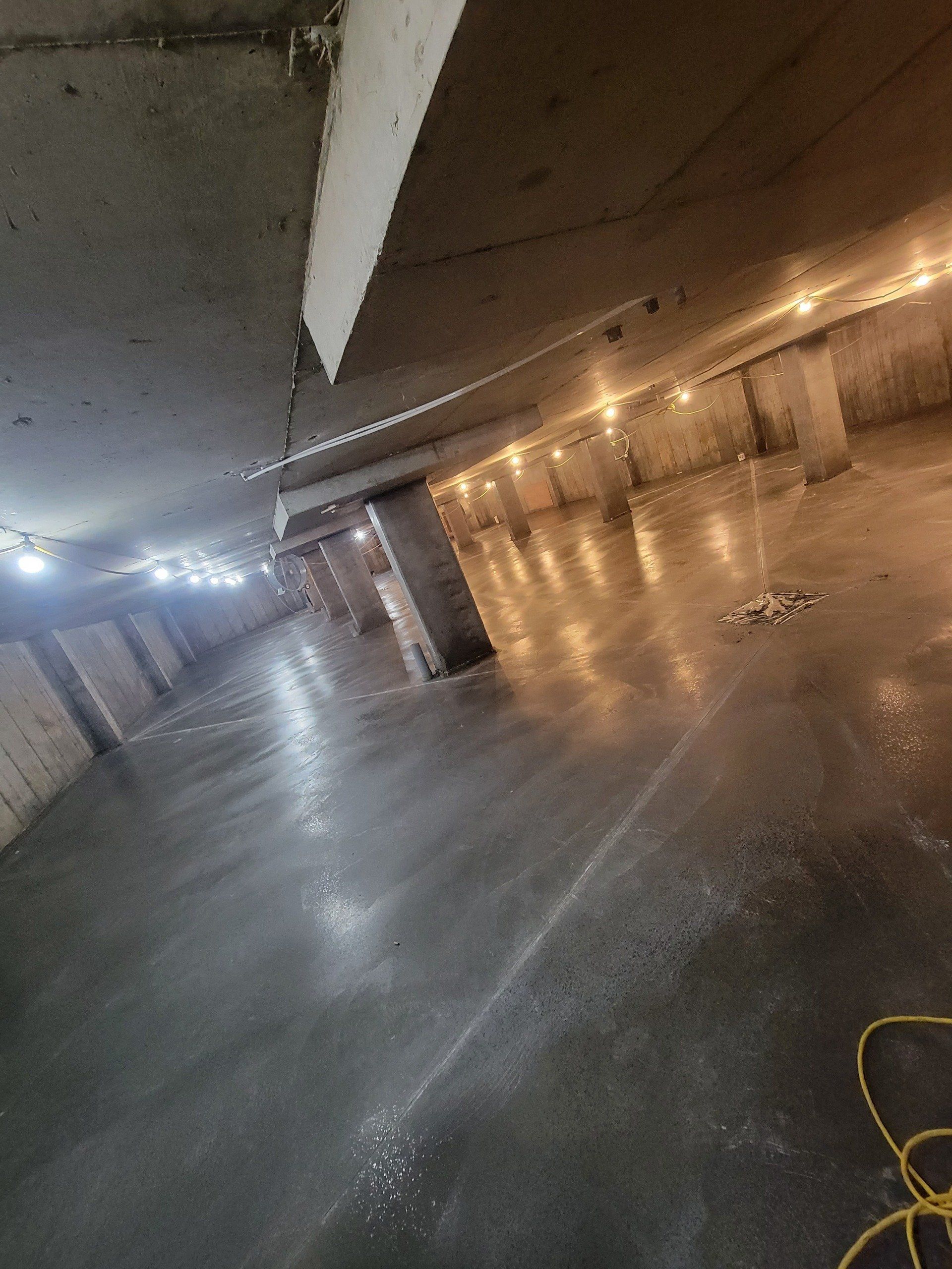 A large empty underground parking garage with a lot of lights on.