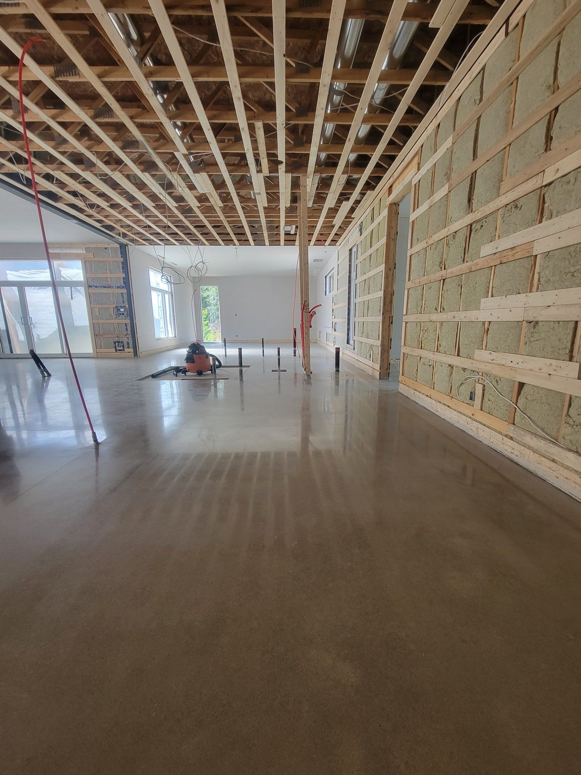 Aménagement intérieur : pièce avec sol en béton, ossature bois apparente au plafond/murs.