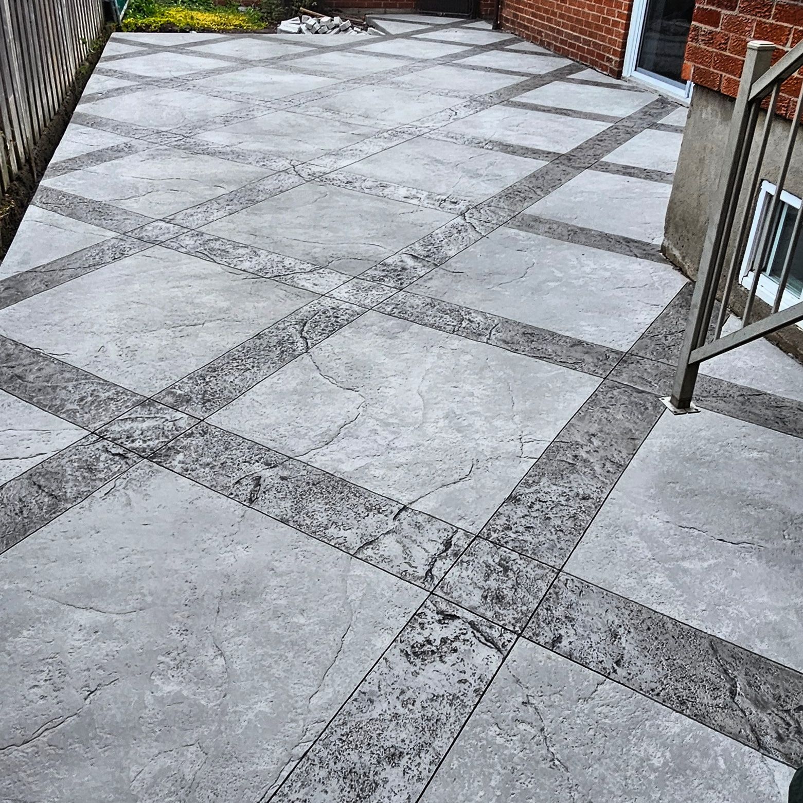 A patio with a brick building in the background and a metal railing.