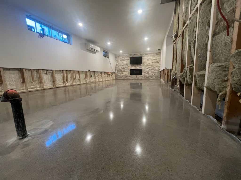 Une grande pièce avec un sol en béton et un mur en briques.