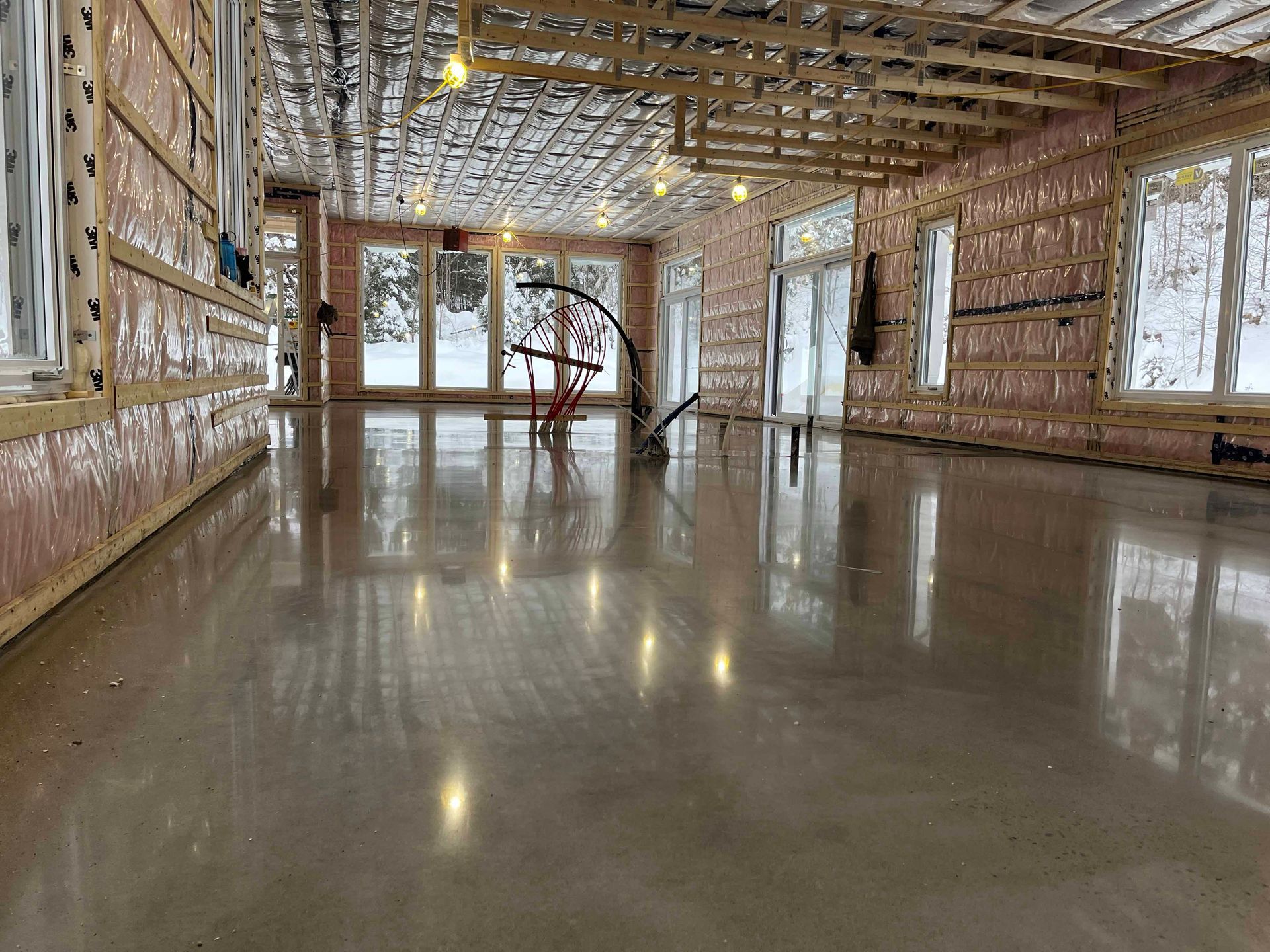 Une grande pièce avec un sol en béton et beaucoup de fenêtres.