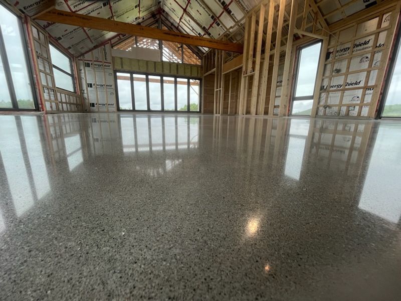 Une grande pièce avec un sol en béton brillant et beaucoup de fenêtres.