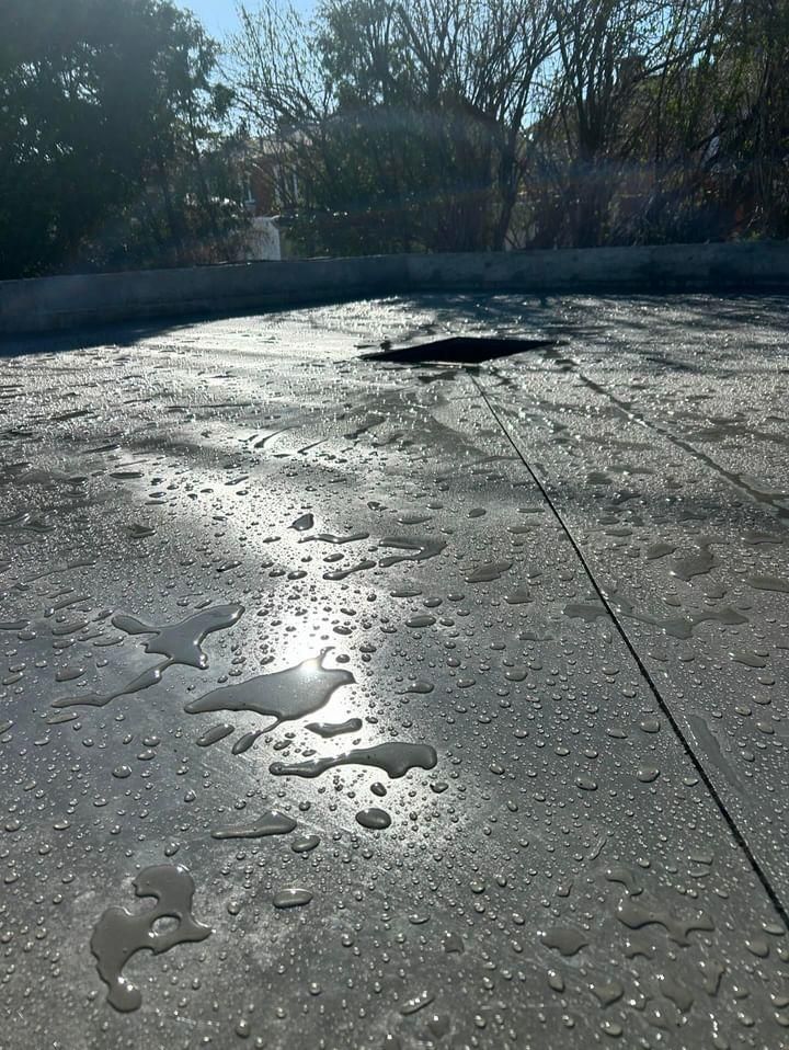 A concrete surface with water drops on it and trees in the background