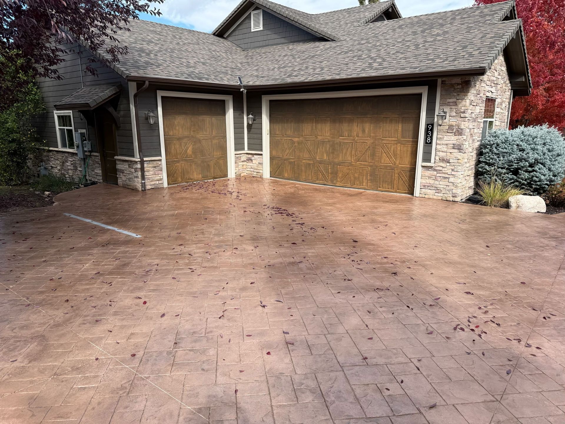 Brown stamped concrete driveway in front of a house with two garage doors.
