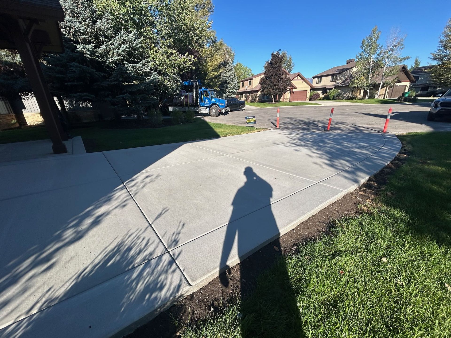 Newly poured concrete sidewalk leading to a residential street, under a bright sky.