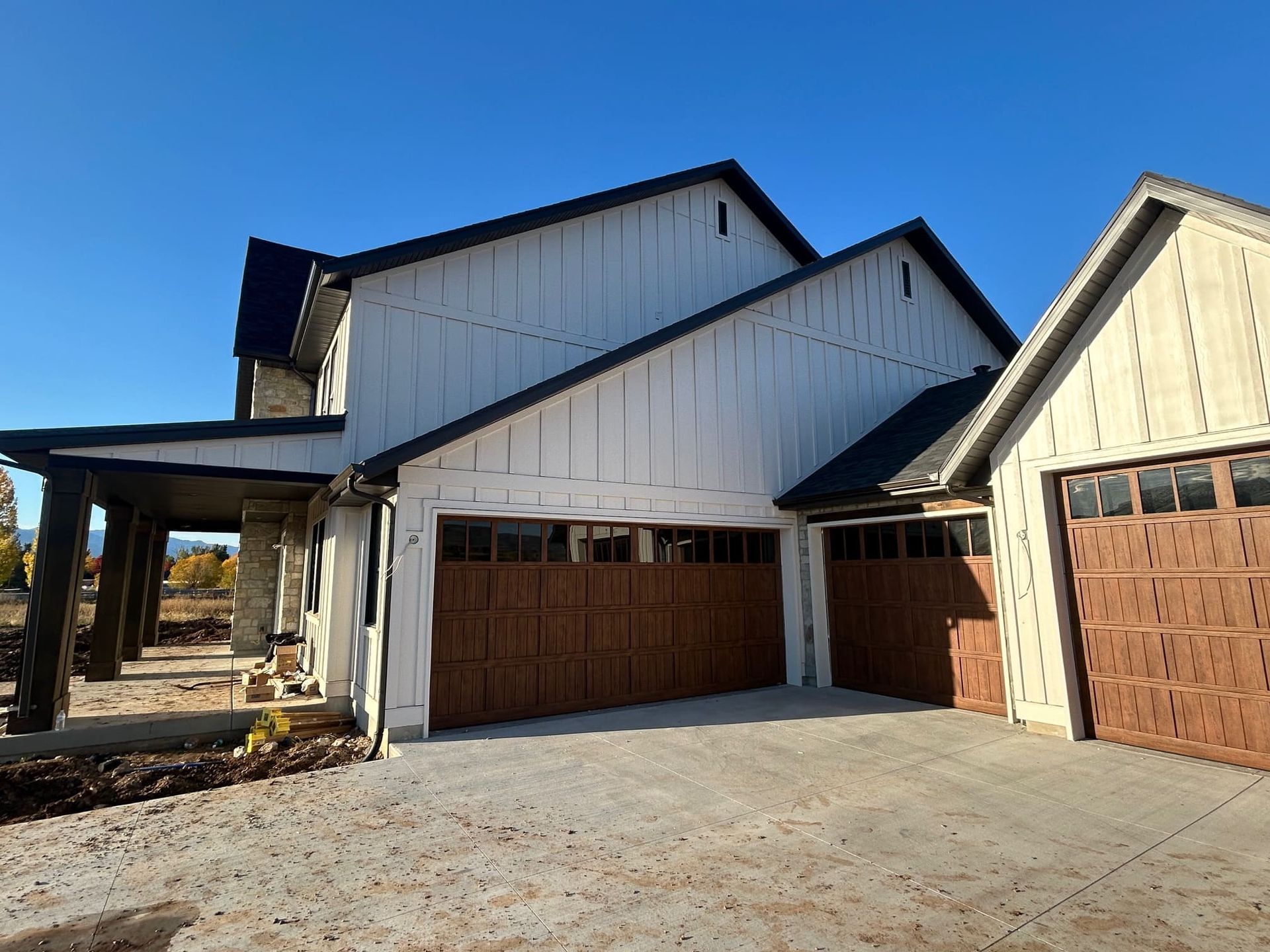 Modern house with white siding, brown garage doors, and a blue sky.