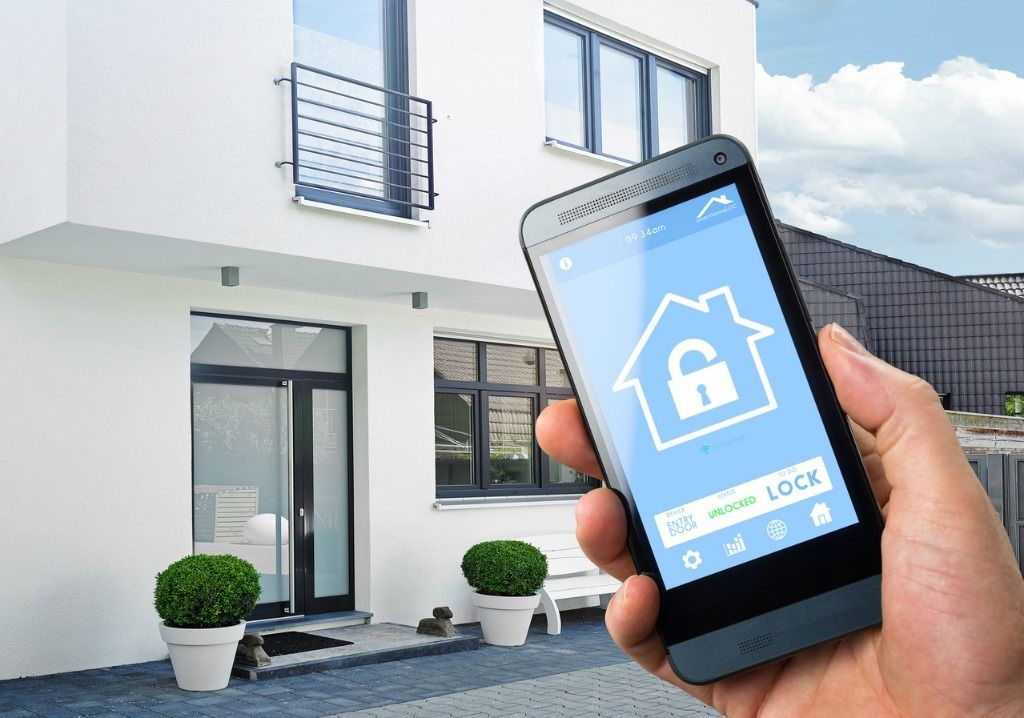 A person is holding a smart phone in front of a house.