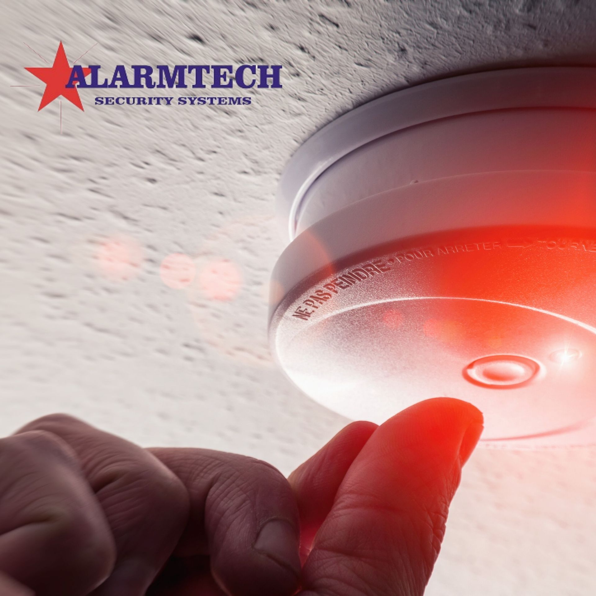 A person is pressing a button on an alarmtech security system