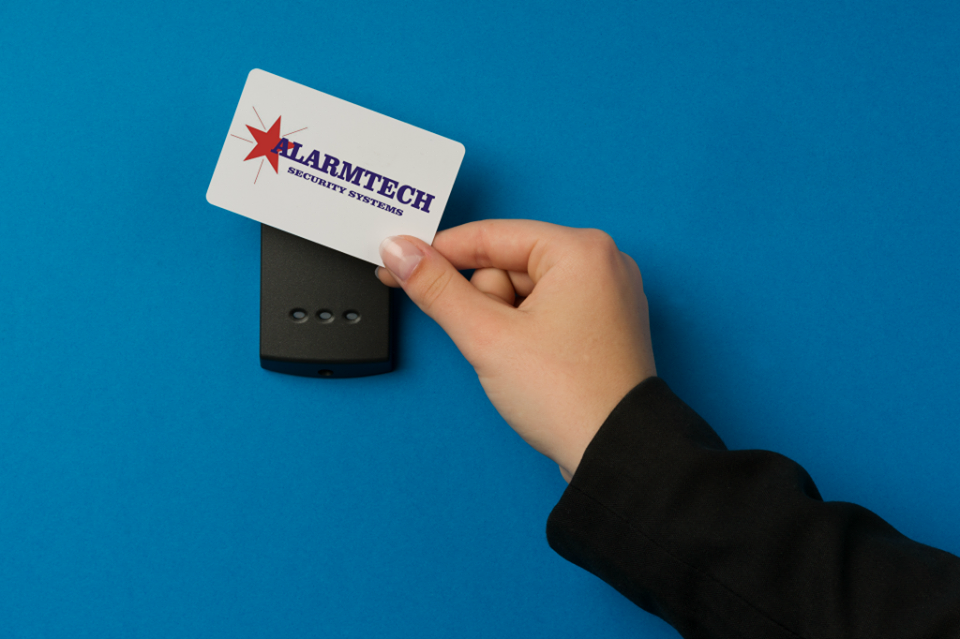 A person is holding a card that says alarmtech on it