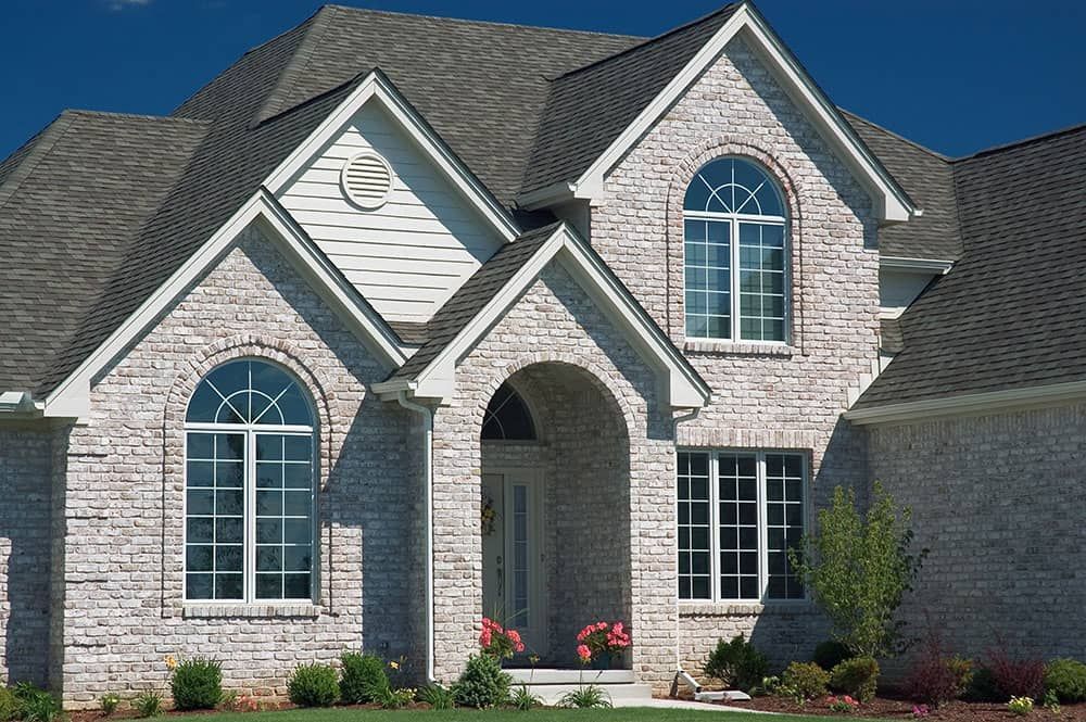 A white brick house with arched windows and a gray roof