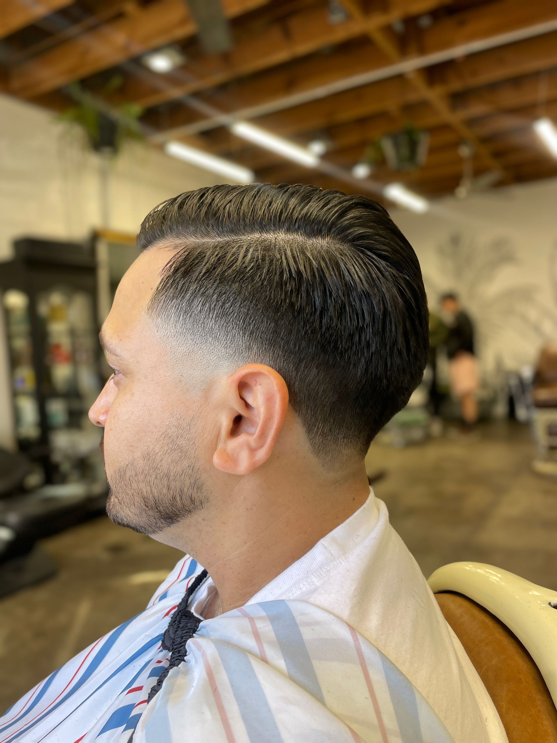 A profile view of a fresh, clean haircut with a sharp side part and a smooth, professional skin fade in a barbershop.
