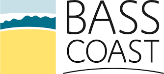 A logo for bass coast with a beach and mountains in the background.