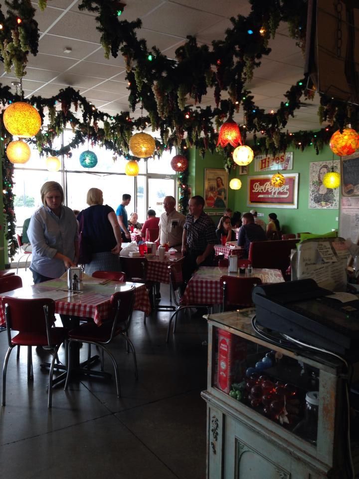 Restaurant interior with people seated at tables; Christmas decorations hang from the ceiling.