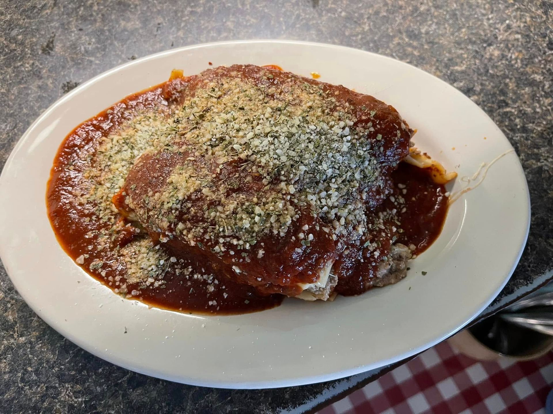Plate of chicken parmigiana with red sauce and parmesan cheese.