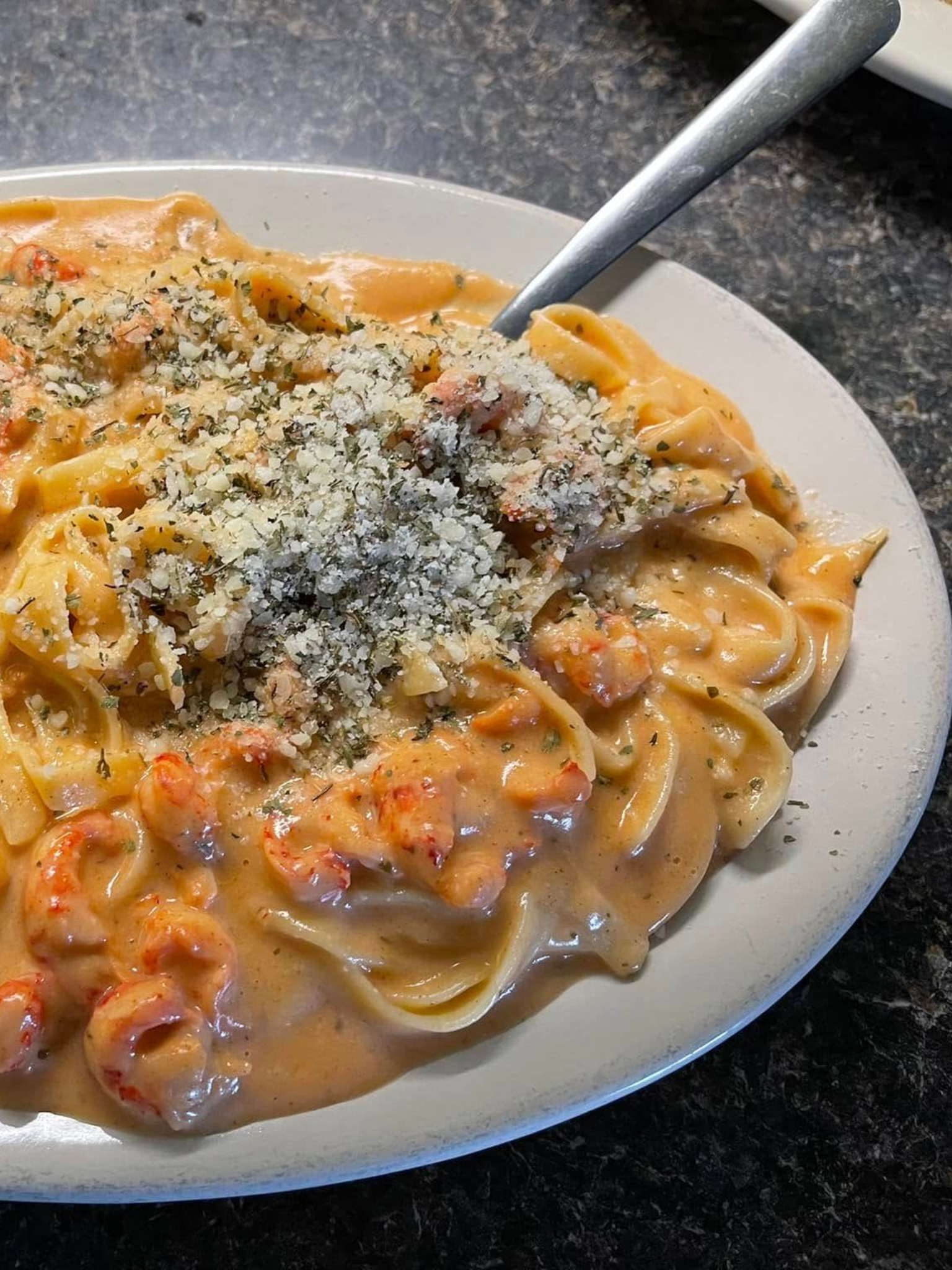 Pasta with a creamy, orange sauce and crawfish, sprinkled with cheese and herbs.