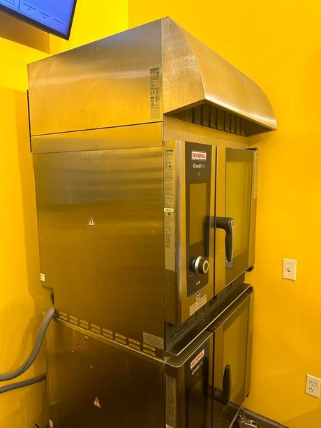 A stainless steel oven is sitting in front of a yellow wall.