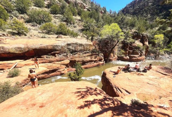 A group of people are standing on top of a rock near a river.