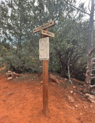 A wooden signpost in the middle of a dirt road.