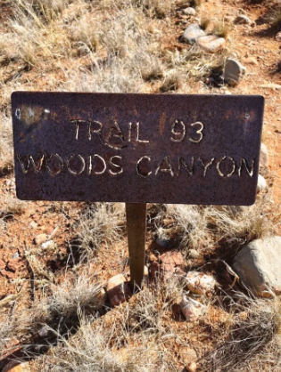 A rusty sign that says trail 93 woods canyon