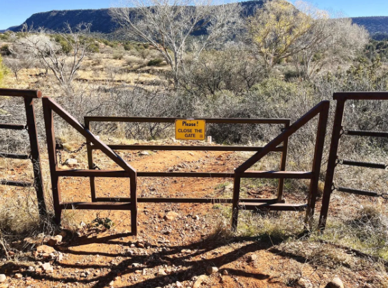 A metal gate with a yellow sign that says road closed