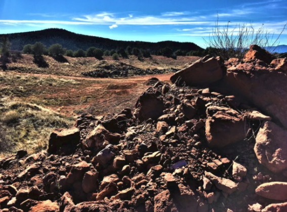 A pile of rocks in a desert with mountains in the background