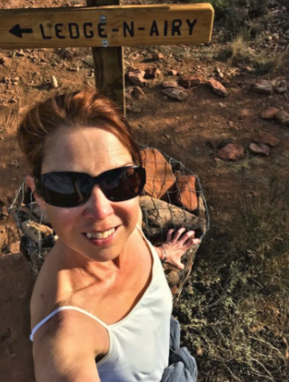 A woman taking a selfie in front of a sign that says ledge-n-airy