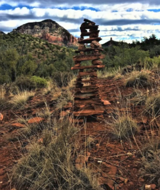 A stack of rocks in the middle of a field with a mountain in the background.