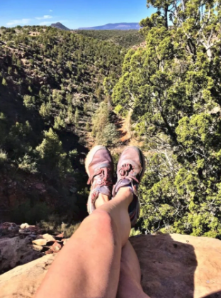A person laying on a rock with their legs crossed
