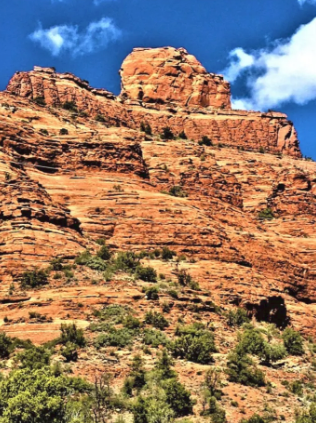 A mountain with a blue sky and clouds in the background