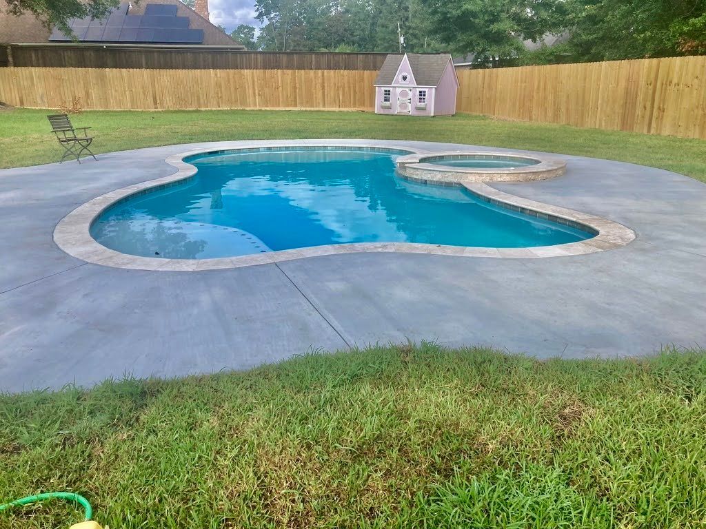 A large swimming pool is surrounded by a wooden fence in a backyard.