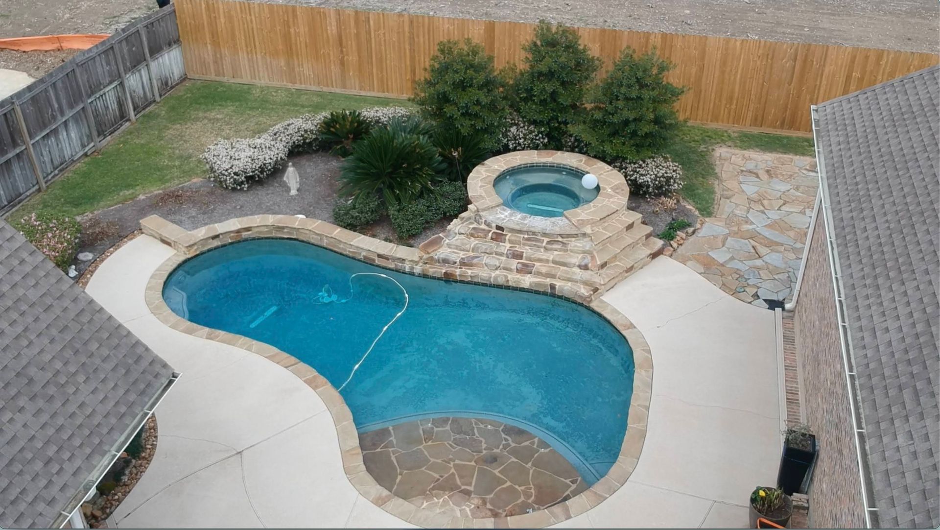 A large swimming pool with a hot tub in the backyard