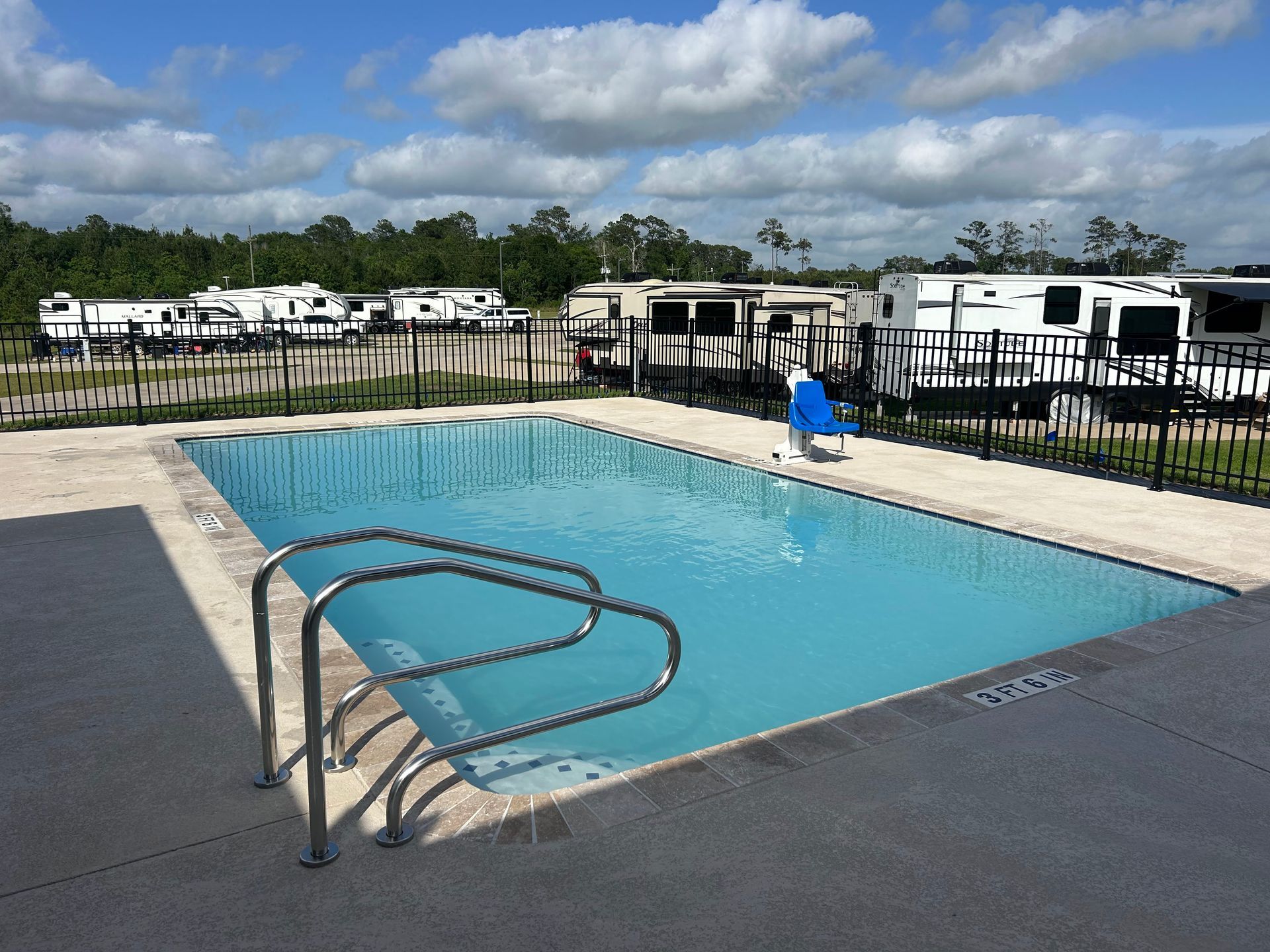 A large commercial swimming pool surrounded by trailers on a sunny day