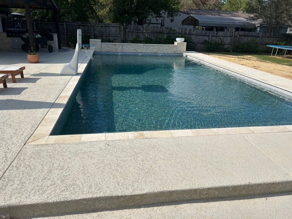 A large swimming pool is surrounded by a concrete patio