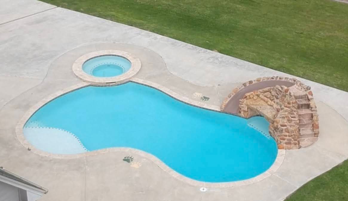 An aerial view of a large swimming pool with a water slide.