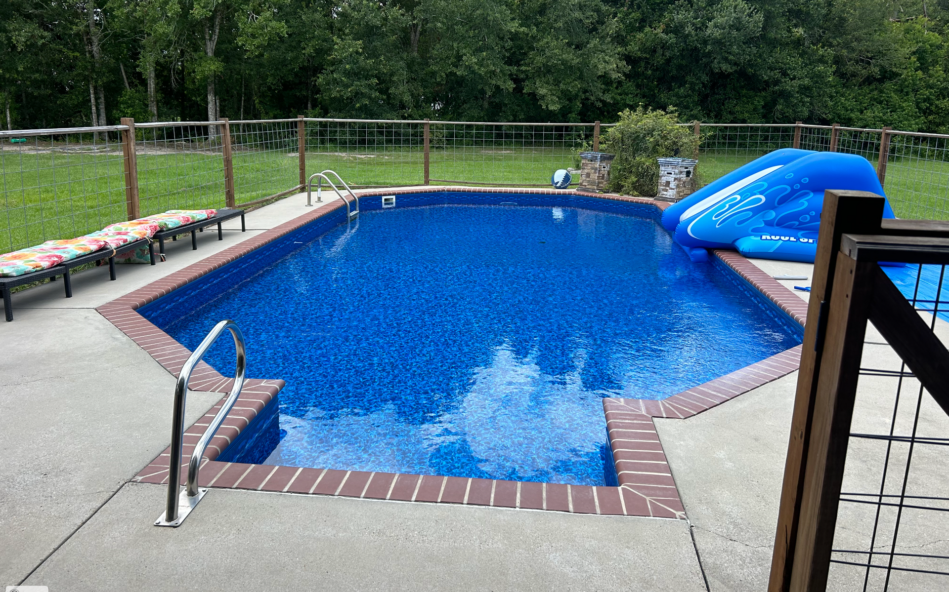 A large blue swimming pool with a slide in the backyard.