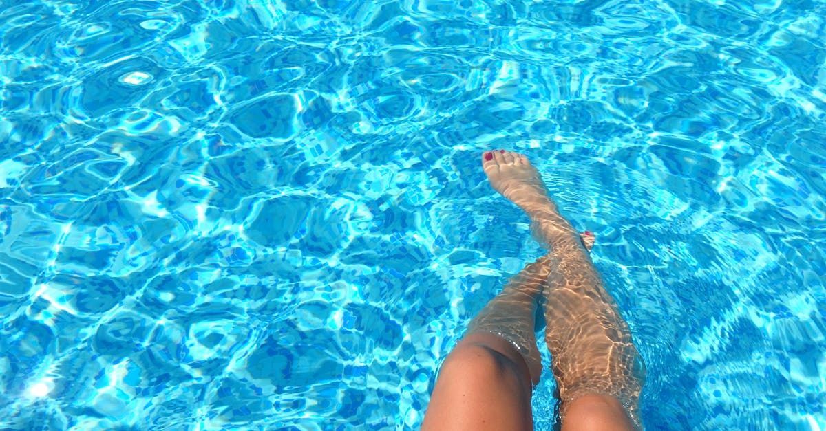 A woman is standing in a swimming pool with her feet in the water.