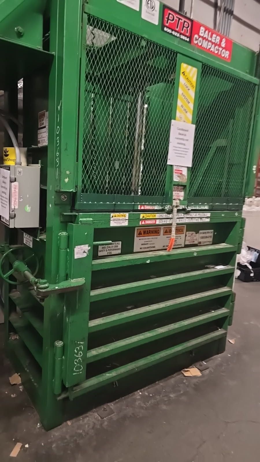 Green industrial cardboard baler in a warehouse.