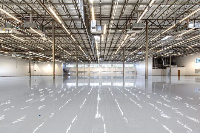 Empty industrial warehouse with polished white floor and exposed ceiling beams